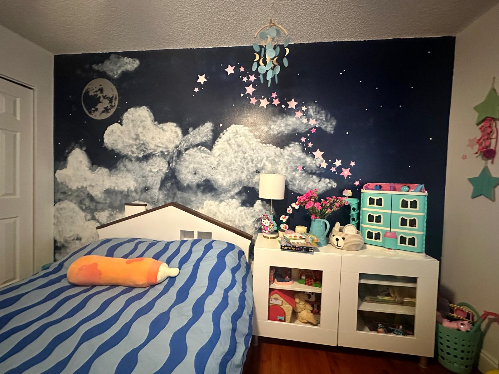 Children’s bedroom mural with a dark blue night sky, textured white clouds, moon and colorful stars.